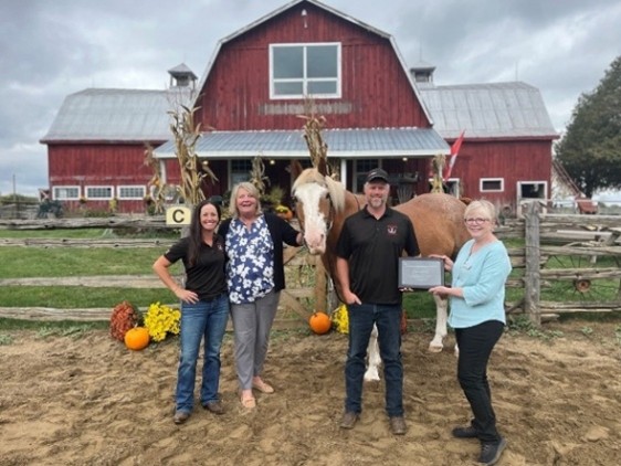 Heritage Stables is presented the 2025 Community Recognition Award by Michele Bellows, CEO, and Sandra Shaw, Board Chair.